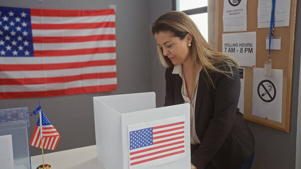 Молодая латиноамериканка, голосующая в избирательном центре колледжа с американскими флагами