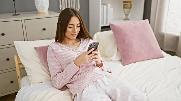 Μια Γυναίκα Πιτζάμες Χρησιμοποιεί Ένα Smartphone Ενώ Κάθεται Ένα Κρεβάτι — Φωτογραφία Αρχείου