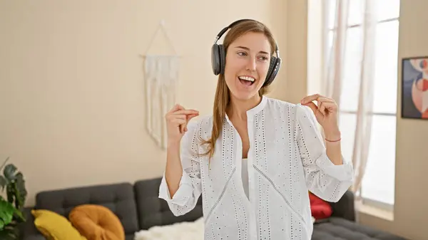 Mujer Joven Sonriente Con Auriculares Disfrutando Música Una Acogedora Sala Imágenes de stock libres de derechos