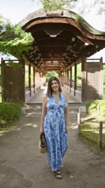 Güzel İspanyol bir kadın, kendinden emin bir şekilde poz veriyor, kameraya gülümsüyor ve geleneksel Kyoto, Japonya 'daki Hian Jingu' ya doğru yürüyor.