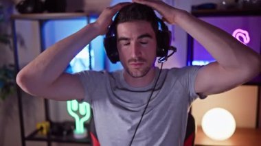 Oyun odasında kulaklık takan yakışıklı bir genç..