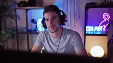 Odaklanmış, kulaklıklı genç bir İspanyol gece karanlık bir odada yoğun bir oyun seansı düzenliyor..