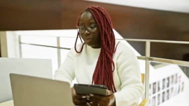 Ofis içinde tablet kullanan örgülü Afrikalı Amerikalı kadın.