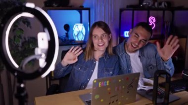 Neşeli bir kadın ve erkek gece vakti iyi donanımlı bir ev yayın stüdyosunda içerik yaratıyor.