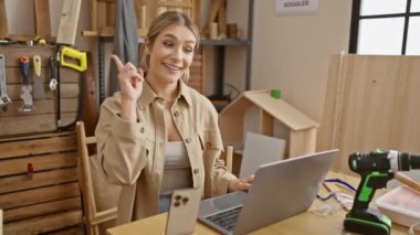 Sarışın, bomba gibi bir marangoz, mesleğinin bir numarası, dizüstü bilgisayarında sörf yaparken parlak bir fikirle şaşırdı, kendine güvenen bir gülümseme ve neşeli bir yüzle işaret etti.