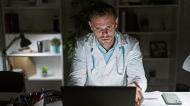 Klinikteki stresli İspanyol doktor geç saatlere kadar bilgisayarla çalışıp hayal kırıklığı ve yorgunluk gösteriyor..