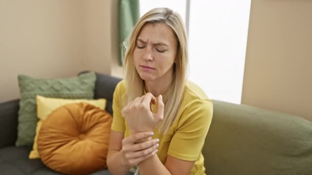 Μια Ανήσυχη Νεαρή Γυναίκα Εξετάζει Τον Καρπό Της Πόνο Κάθεται — Αρχείο Βίντεο