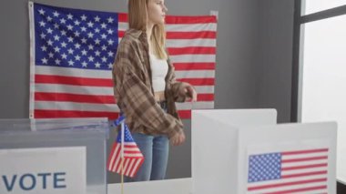 Beyaz bir kadın seçim odasında ABD bayrağı ve oy kabinleriyle silah çekerek vatandaşlığı ve demokrasiyi yansıtıyor..
