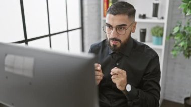 Ofis masasında çalışan ve duygularını ifade eden sakallı profesyonel bir adam..