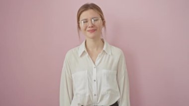 Sarışın, havalı ve kendine güvenen genç bir kadın mükemmel dişlerini gösteren mutlu bir gülümseme sergiliyor. Ayakta, gözlüklü, pembe bir arka planda ışıldayan. 