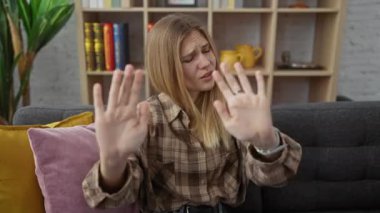 Çekici genç sarışın, öfke ve hüsran saçan, oturma odasındaki kanepede oturan, 