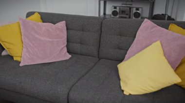 Genç bir adam renkli yastıklarla çevrili koltuğunda kendini perişan hisseder.