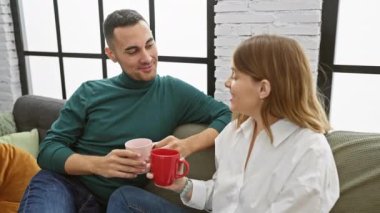 Bir çift sıcak oturma odasındaki kanepede kahve içip, keyifli bir anı paylaşıyor..