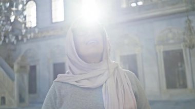 Bir tesettür içinde gülümseyen bir kadın tarihi İstanbul camiinin iç dekorasyonuna hayran, huzur ve maneviyat yayıyor..