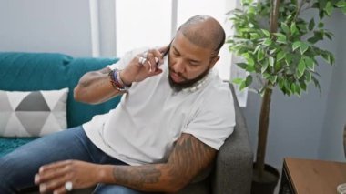 Sakallı, yetişkin bir zenci, kapalı bir koltukta otururken akıllı bir telefonla konuşur..