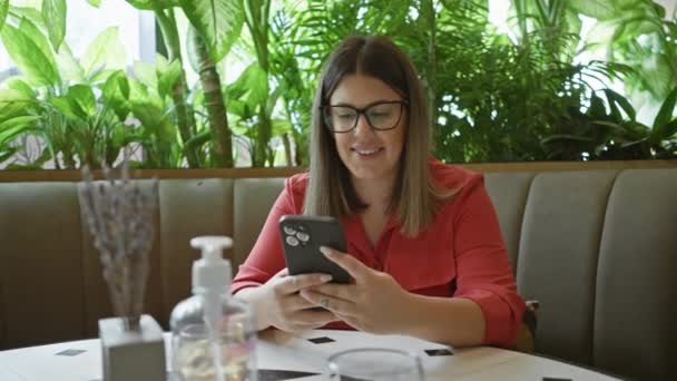 Leende Kvinna Med Hjälp Smartphone Café Omgiven Gröna Växter — Stockvideo