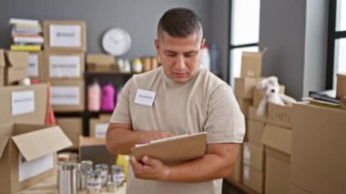 Gönüllü olarak gülümseyen kendine güveni tam genç Latin bir adam, çabukluk merkezindeki hayır işleri listesine yazarak eğleniyor.