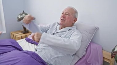 Pijama giyen, kuşkucu, son sınıf öğrencisi yüzünde gergin ve onaylanmayan bir ifadeyle. Yatak odasında kollarını kavuşturup negatif bir insanı canlandırıyor..