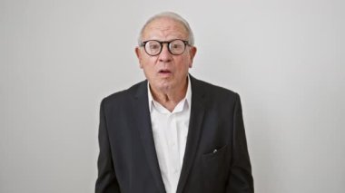 İş kıyafetleri içinde korkmuş yaşlı bir adam yüzünü eliyle kapatıyor. İzole edilmiş beyaz arka planda parmaklarının arasından şoka giriyor.