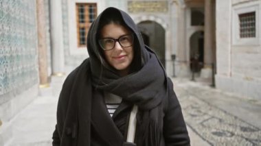 Tarihi Türk sarayında gözlük ve eşarp takan gülümseyen kadın süslü fayanslar ve mimariyle.