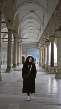 İstanbul 'daki antik Osmanlı mimarisinde gözlüklü ve başörtülü gülümseyen kadın..