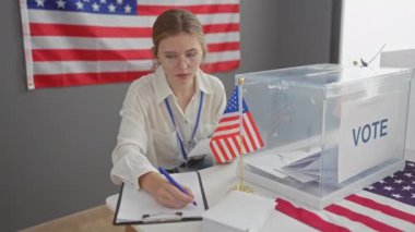 Genç bir kadın, seçim sürecini gösteren bir Amerikan bayrağıyla ABD 'deki bir oy kullanma merkezinde oy kullanırken görülüyor..