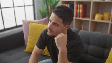 Yakışıklı, sakallı, modern bir oturma odasında kafa yoran bir İspanyol.