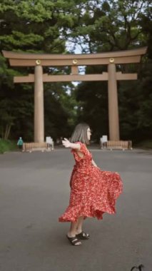 Neşeli İspanyol kadın kollarını açmış gülümsüyor, Meiji tapınağına bakıyor, kendine güvenini ve mutluluğunu gösteriyor.