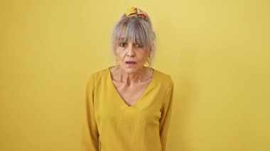 Gri at kuyruklu kızgın orta yaşlı kadın kameraya kızgın bir şekilde seni suçluyor! İzole edilmiş sarı arka plan çığlıklarına karşı hayal kırıklığına uğramış duruş hoşnutsuzluk.