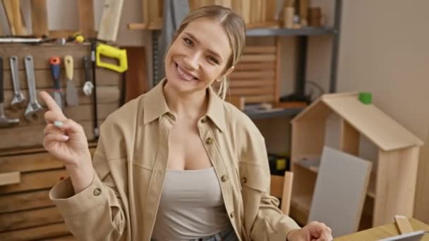 Jovem Mulher Loira Alegre Senta Sua Oficina Carpintaria Apontando Com — Vídeo de Stock