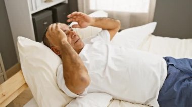 Rahat, orta yaşlı, rahat giyinmiş, havadar bir odada rahat bir şekilde yatan İspanyol bir adam.