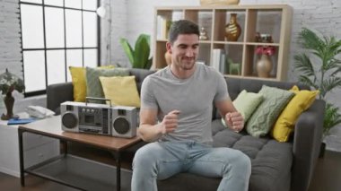 Mutlu bir adam, modern dekorlu rahat bir oturma odasında müzik eşliğinde dans eder..