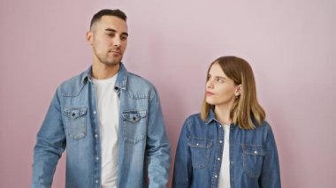 Kot gömlekli güzel bir çift şüphe içinde, ayakta, başbaşa, düşünceli bir şekilde pembe izole edilmiş arka plana bakıyorlar.