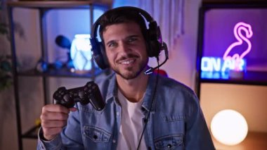 Oyun odasında sakallı yakışıklı oyuncu geceleri kumandayı tutuyor, boş zamanlarını ve teknolojiyi canlandırıyor..