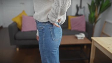 Rahat bir oturma odasında akıllı telefonunu kullanan genç bir kadın rahat ve rahat bir hava yayıyor..