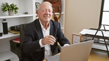 Ofiste dizüstü bilgisayarla çalışırken boyun ağrısı çeken stresli yaşlı bir adam.