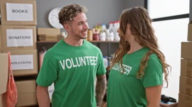 Gönüllü gömlekler giyen genç bir adam ve kadın bağış merkezinde üzerinde 