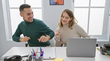 Bir erkek ve kadın, parlak bir ofis ortamında neşeli bir şekilde etkileşime geçerek, iş yerinde takım çalışması ve çatışma öneriyorlar..