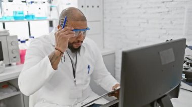 Sakallı bir bilim adamı modern bir laboratuvar ortamında bilgisayardaki verileri analiz eder..