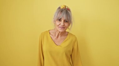 Gri at kuyruklu, kendinden geçmiş orta yaşlı bir kadın neşeli bir şekilde başarısını sergiliyor. Sarı izole zemin üzerinde neşeli onay işareti.