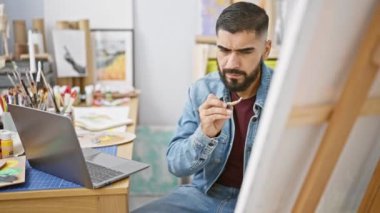 Bir sanat stüdyosunda, sakal, kot, sehpa, dizüstü bilgisayar, yaratıcılık, kapalı alan, sanatçı, fırça, odaklanma, erkek.