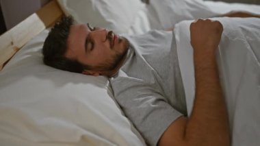 Sakallı, evde rahat bir yatak odası tasvir eden, rahat, genç, İspanyol bir adam..