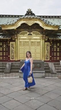 Gözlüklü güzel İspanyol kadın Tokyo, Ueno Park Tapınağı 'nda elbisesiyle sevinçle dönüyor. Canlı ruhu şehir ortamında dans ediyor, Japonya 'nın benzersizliğini yakalıyor..