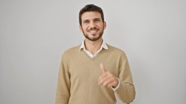 Süveter giyen genç İspanyol adam mutlu ve pozitif gülümsüyor, başparmağı yukarıda, izole edilmiş beyaz arka plan üzerinde mükemmel ve onay işareti yapıyor.