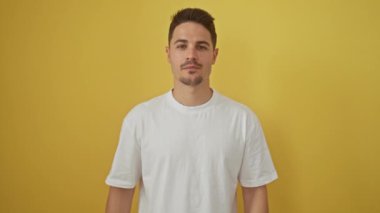 Beyaz tişörtlü neşeli, genç İspanyol bir adam başarılı bir fikirle akıllı bir şekilde parmağını kaldırdı. Heyecanlı, ışıldayan bir numara, parlak sarı bir arka planda tek başına..