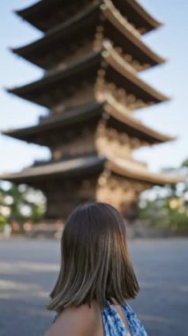 Güzel İspanyol kadın ayakta, güvenle gülümsüyor Japonya 'nın To-ji tapınağının önünde, mutluluk ve kaygısız neşe saçıyor, dostça ifadesi bu Kyoto parkını daha da eğlenceli hale getiriyor..