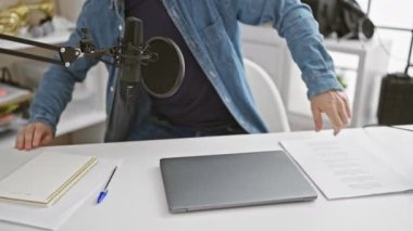 Stüdyoda mikrofon ve dizüstü bilgisayarlı kel bir adam podcast kaydına hazırlanıyor..