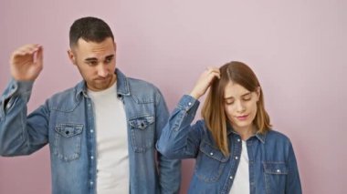 Kot gömlekli güzel bir çift şaşkın, pembe arka planda duruyorlar, derin bir şüphe içindeler - belirsiz bir aşkın görüntüsü, ilişkinizi sorguluyorlar.?