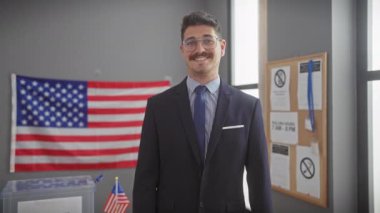 Takım elbiseli bir adam, Amerikan bayraklarıyla kameraya bakıp liderlik ve demokrasiyi iletiyor..
