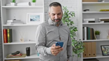 Kendine güveni tam, sakallı, gri saçlı, modern ofis ortamında....